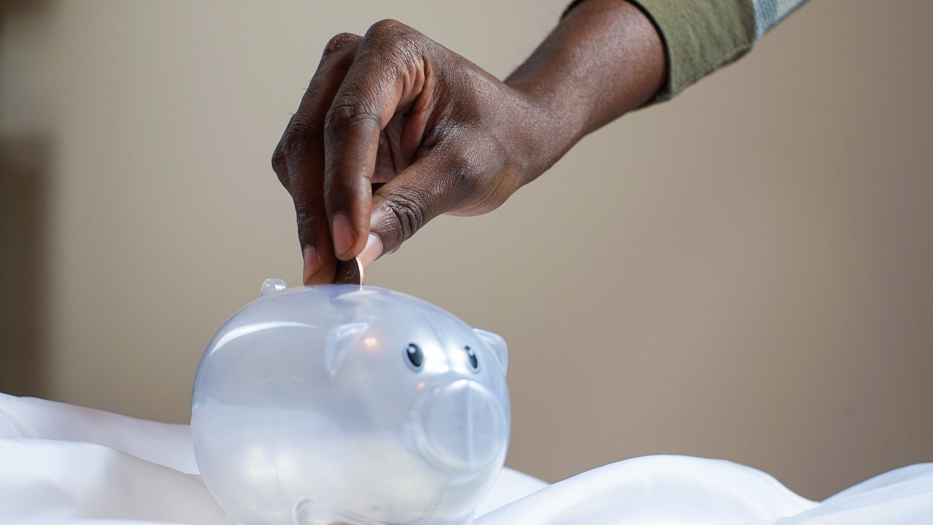 Saving money by putting coins into a piggy bank