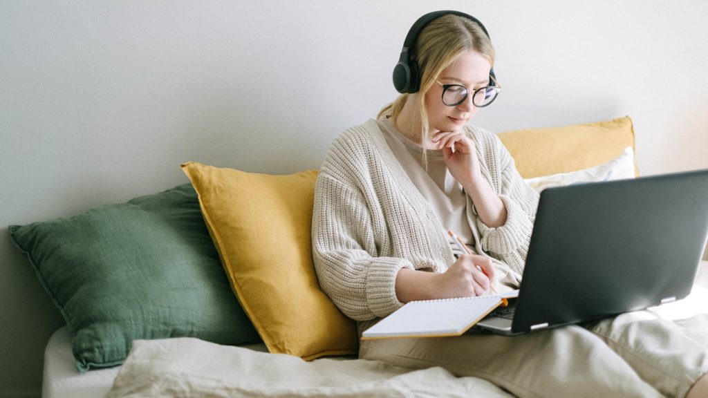 Woman wearing a thick sweater while working on her couch