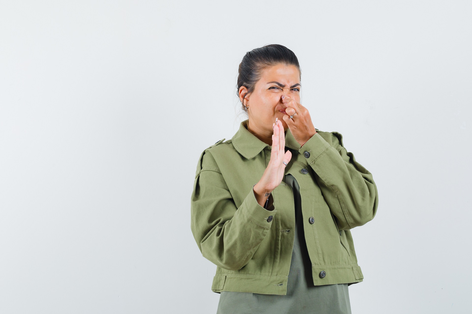Woman plugging nose due to bad smell coming from the sink drain