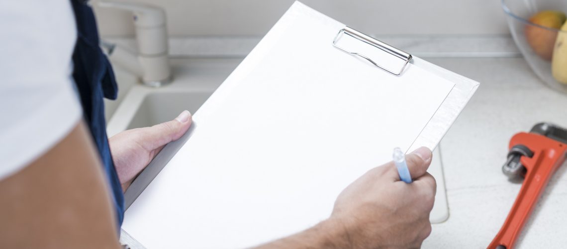 Plumber holding clipboard making list of plumbing issues