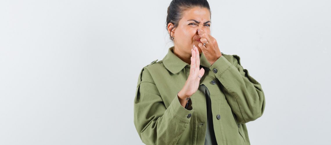Woman plugging nose due to bad smell coming from the sink drain