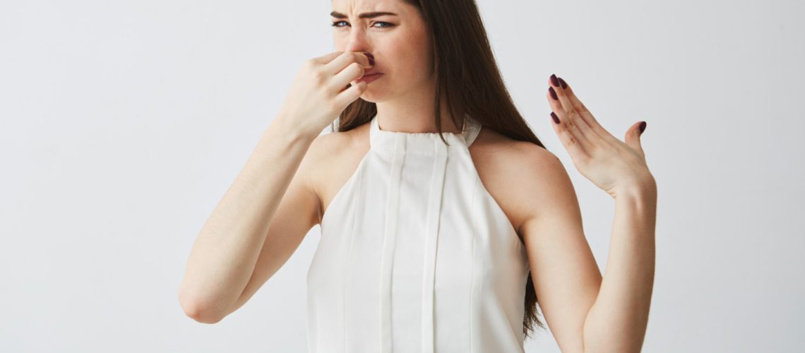 Woman plugging her nose because she smells rotten eggs from her gas furnace
